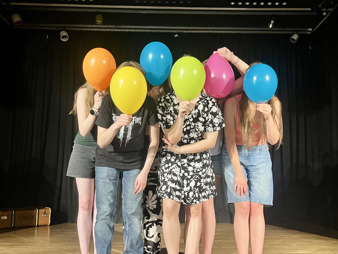 Gruppenbild mit Ballons vor den Gesichtern